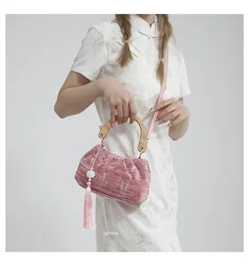 Pink velvet pleated handbag with wooden handle and tassels paired with white Qipao