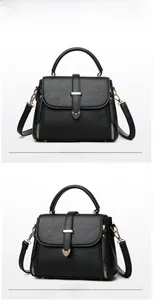 Close-up of black textured leather handbag with gold heart lock and metallic details
