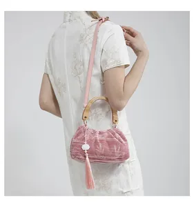 Detail of pink velvet cloud bag with bamboo handle and elegant white floral tassel