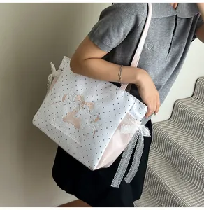 Détail de la broderie lapin rose et dentelle sur un sac cabas en toile à pois blancs