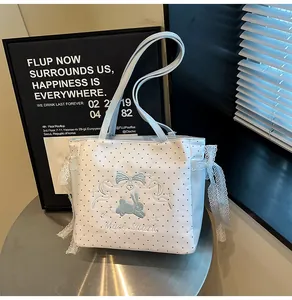 Détail du sac cabas à pois bleus avec broderie lapin et accents de nœuds en dentelle