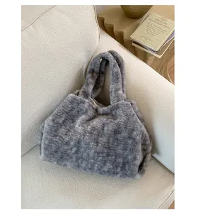 Close-up of the dense curly faux fur texture on a grey plush tote bag on a sofa