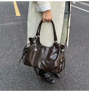 Détail du sac cabas en cuir ciré marron foncé avec breloque étoile et chaîne argentée