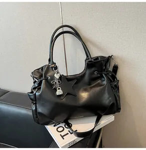 Détail du sac cabas en cuir noir avec breloques étoiles argentées et texture souple