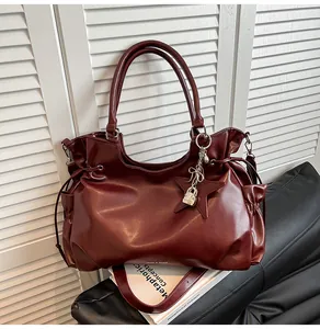 Détails d'un sac cabas en cuir bordeaux avec plis subtils et pendentif étoile