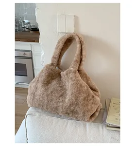 Close-up of a large fuzzy plush tote bag in khaki faux fur on a cozy sofa