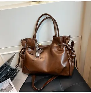 Détail du sac cabas en cuir ciré marron foncé avec breloque étoile et fermoir métal