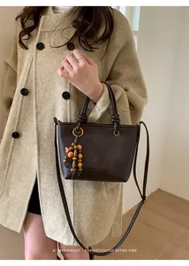Close-up of retro dark brown tote with bead tassel worn on beige wool coat