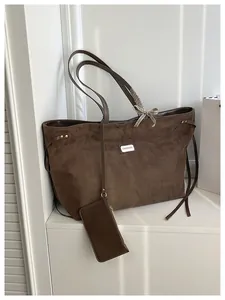 Nahaufnahme der braunen Veloursleder-Tragetasche mit FASHION-Label und Karoschleife
