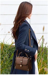Detail view of dark brown lychee leather crossbody bag worn by a model in natural light