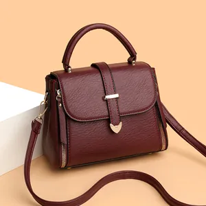 Detailed close-up of dark wine red lychee grain leather bag with golden heart buckle