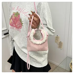 Detailed close-up of pink suede dumpling bag with soft white faux shearling handle