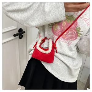Detail of red suede dumpling bag with white faux fur trim and adjustable strap