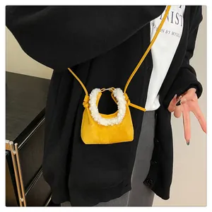 Detail of yellow suede dumpling bag with fluffy white faux fur handle and knot strap