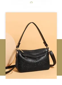 Détail du sac bandoulière en cuir noir avec gaufrage rose 3D et finitions dorées