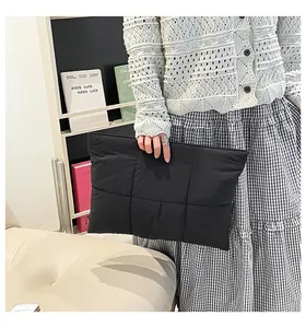 Close-up of black quilted puffer laptop sleeve with square stitching and soft nylon texture