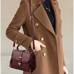 French retro burgundy leather shoulder bag with gold heart buckle worn on tweed coat