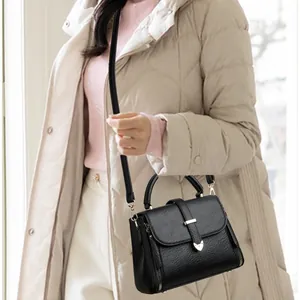 Minimalist black lychee texture handbag with gold hardware shown in a lifestyle setting