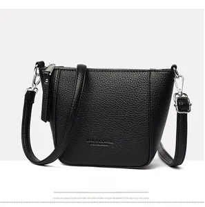 Close-up of black lychee grain leather texture and adjustable strap on a bucket bag