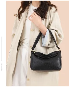 Détail du sac à bandoulière en cuir noir avec gaufrage rose et multiples zips