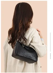 Gros plan du sac bandoulière en cuir noir avec motif de camélia en relief