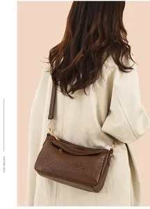 Détails du sac bandoulière marron foncé avec gaufrage rose et ferrures métalliques dorées
