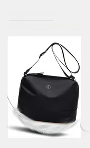 Close-up of black crossbody bag showing the metallic logo and durable nylon texture