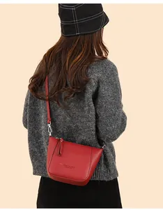Close-up of red lychee textured crossbody bag styled with a grey knit sweater