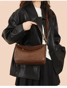 Détail du sac en cuir marron foncé avec gaufrage rose et bandoulière réglable