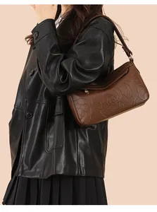 Détail du motif rose en relief sur sac à bandoulière en cuir marron avec fermeture éclair