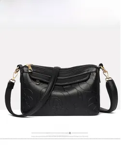 Détail de sac à main en cuir noir avec motif floral en relief et fermetures éclair dorées