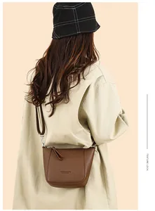 Brown litchi texture bucket bag shown on a model with minimalist beige clothing