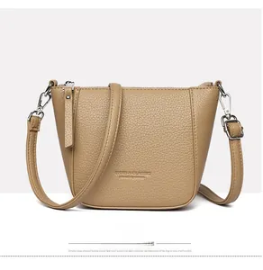 Front view of khaki lychee leather bucket bag with silver zippers and adjustable strap