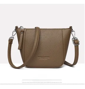 Detailed view of brown litchi grain leather texture and embossed silver zipper on bucket bag