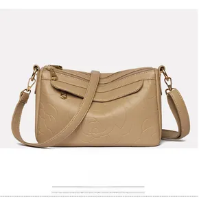 Gros plan du motif camélia gaufré sur le sac en cuir beige à grain litchi