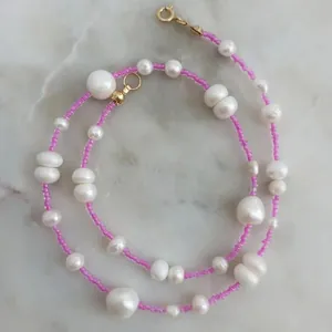 Detail of pink glass beads and irregular freshwater pearls on a handmade gold clasp necklace