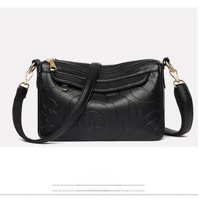 Détail du sac à main noir en cuir grainé avec motif rose en relief et finitions dorées