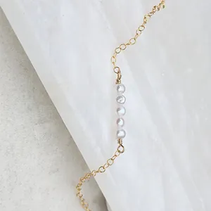 Detail of 18k gold plated chain featuring five natural freshwater pearls on marble