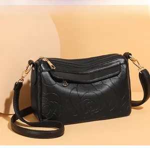 Détail du motif rose gaufré sur cuir et ferrures dorées du sac bandoulière noir