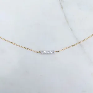 Detailed macro view of delicate gold chain necklace with five natural freshwater pearls