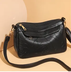 Détail du sac à main en cuir noir avec motifs de camélia en relief et finitions dorées