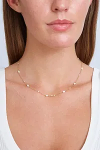 Close-up of elegant gold plated chain necklace featuring natural freshwater pearls on model