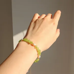 Détail du bracelet en perles d'eau douce et gravier vert au poignet avec chaîne dorée