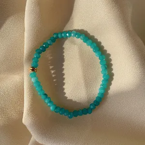 Macro shot of turquoise beaded bracelet with faceted stones on champagne silk fabric