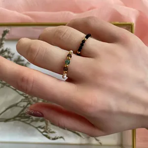 Detail of handmade beaded ring set with colorful natural stones and gold beads on a model