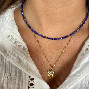 Close-up of layered bohemian beaded necklace with evil eye pendant and gold charms