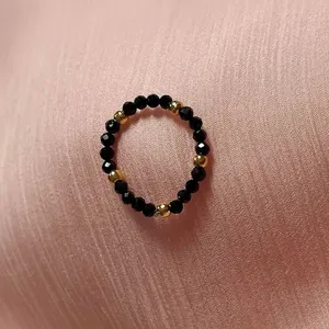 Detail of handcrafted beaded ring with faceted black stones and golden metallic beads