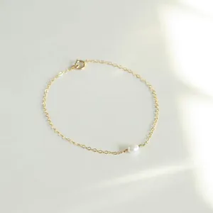 Macro detail of 18k gold plated chain featuring a natural freshwater pearl centerpiece