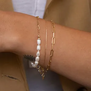 Detailed layered set of 18k gold plated paperclip and freshwater pearl bracelets on wrist