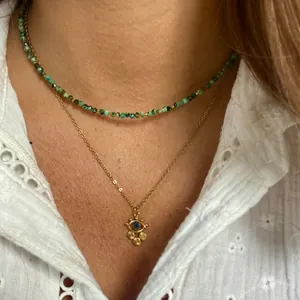 Close-up of layered necklace set featuring green beads and a golden evil eye pendant